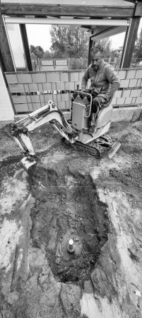 Téléchargez les photos : Worker drilling a well under water. Installing the system for outdoor garden irrigation. - en image libre de droit