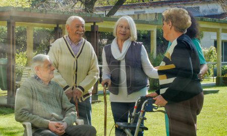 Téléchargez les photos : Infirmière africaine parlant à deux couples retraités âgés en plein air dans le jardin de l'hôpital de réadaptation. Concept de bonheur, de réadaptation et de retraite. - en image libre de droit