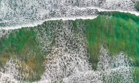 Foto de Overhead aerial view of gentle waves along the beautiful shoreline. - Imagen libre de derechos
