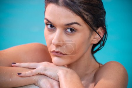 Téléchargez les photos : Belle fille caucasienne se détendre dans un spa, regardant vers la caméra, piscine en arrière-plan. - en image libre de droit