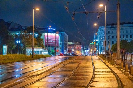 Photo for Vienna, Austria - August 22, 2022: City streets on a rainy night with tram railway. - Royalty Free Image