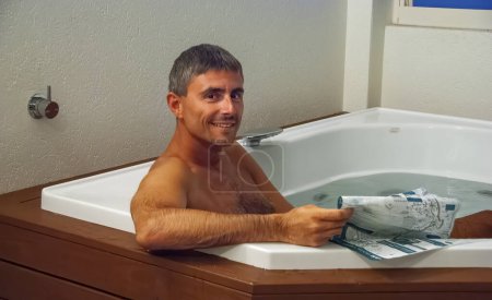 Téléchargez les photos : Portrait d'un homme caucasien heureux se détendre dans le tourbillon de l'hôtel la nuit. - en image libre de droit