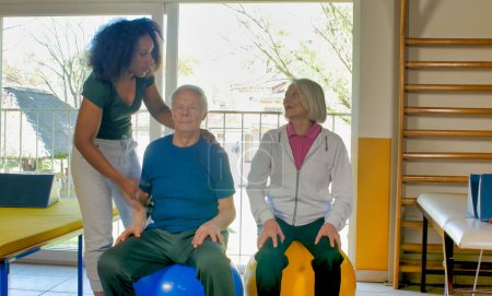 Rehabilitation concept. Elderly couple in a gym supervised by expert african female trainer.