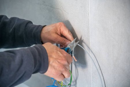 Foto de Electrician mounts an electrical outlet to the wall. - Imagen libre de derechos