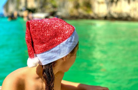 Téléchargez les photos : Noël tropical familial. Joyeux jeune fille portant chapeau de Noël sur une belle plage. - en image libre de droit