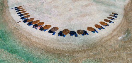Foto de Vista aérea de una fila de sombrillas a lo largo de una hermosa playa con aguas cristalinas. - Imagen libre de derechos