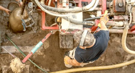 Téléchargez les photos : Workers drilling a well under water. Installing the system for outdoor garden irrigation. - en image libre de droit