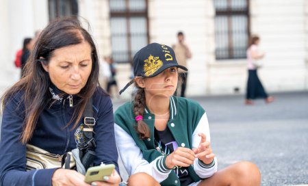 Téléchargez les photos : Touristes en Europe. Jeune fille avec sa mère relaxante assise dans la rue. - en image libre de droit