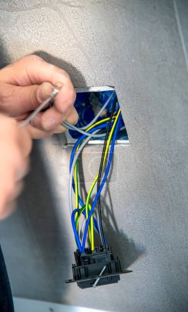 Foto de Electricista monta un enchufe eléctrico a la pared, cables de conexión. - Imagen libre de derechos