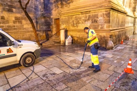 Photo for Granada, Spain - April 13, 2023: Street worker cleans the streets at night. - Royalty Free Image