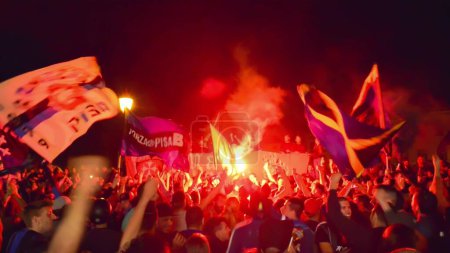 Foto de PISA, ITALIA - 15 DE JUNIO DE 2016: Los aficionados locales celebran la promoción del equipo de fútbol. Celebraciones en la noche con bombas de humo y un autobús abierto. - Imagen libre de derechos