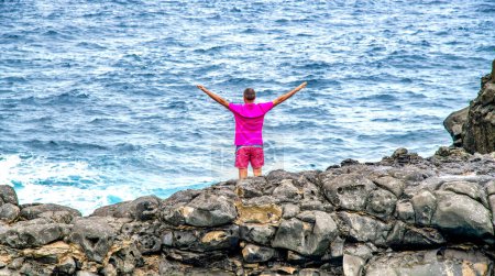 Photo for Man relaxing and embracing nature standing on the rocks above the ocean. Holiday concept - Royalty Free Image