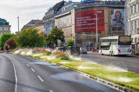 Téléchargez les photos : Vienne, Autriche - 19 août 2022 : Des plates-bandes mouillées par les éclaboussures d'eau en saison estivale sur une grande route urbaine. - en image libre de droit