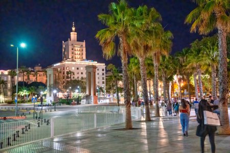 Photo for Malaga, Spain - April 14, 2023: Tourists walk along the city port promenade at night. - Royalty Free Image