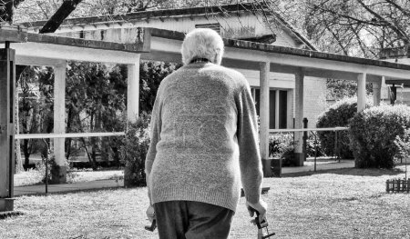 Téléchargez les photos : Homme retraité âgé avec marcheur se promenant dans le jardin. - en image libre de droit