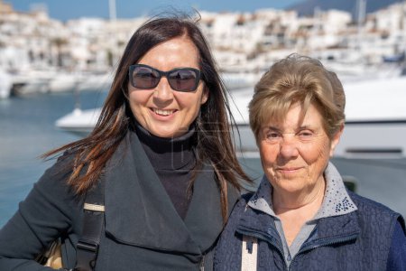 Téléchargez les photos : Une retraitée âgée en vacances avec sa fille, un port de la ville en arrière-plan. - en image libre de droit