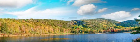 Téléchargez les photos : Vue aérienne panoramique du lac et des arbres dans la mer de feuillage d'automne contre ciel bleu. - en image libre de droit