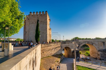 Téléchargez les photos : Cordoue, Espagne - 11 avril 2023 : Les touristes marchent le long du pont romain au coucher du soleil. - en image libre de droit