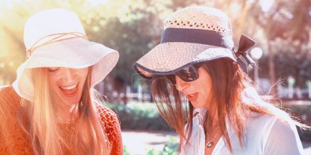 Photo for Couple of girls smiling outdoor looking at something. - Royalty Free Image