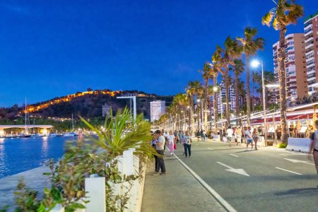 Photo for Malaga, Spain - April 14, 2023: Tourists walk along the city port promenade at night. - Royalty Free Image