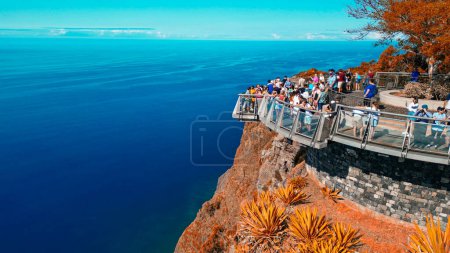 Tourists enjoy the viewpoint at Cabo Girao, along the Madeira coastline, Portugal. Aerial view from drone.