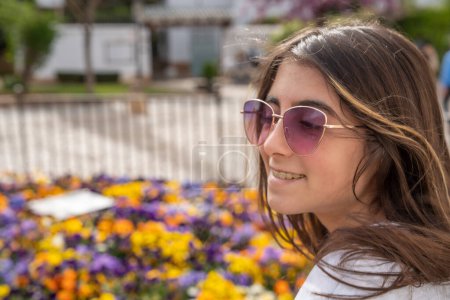Foto de Una joven feliz con un fondo de flores de colores. - Imagen libre de derechos
