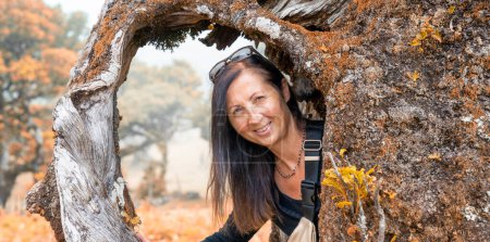 Téléchargez les photos : Portrait de femme encadré à l'intérieur des racines d'un tronc d'arbre. - en image libre de droit