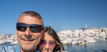Téléchargez les photos : Un homme heureux en vacances avec sa fille, un port de la ville en arrière-plan. - en image libre de droit