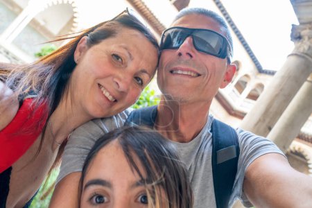 Téléchargez les photos : Une famille de deux adultes et leur fille prenant selfies dans le Real Alcazar de Séville. - en image libre de droit