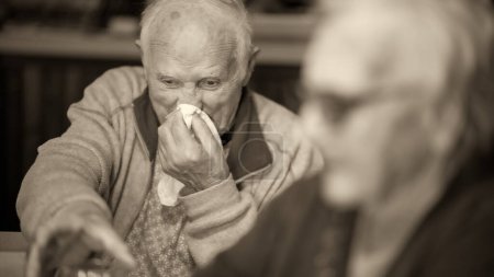 Téléchargez les photos : Un vieil homme avec un rhume se fait mal au nez à la maison. - en image libre de droit