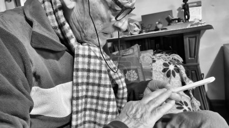 Photo for An elderly man files his fingernails at home. - Royalty Free Image