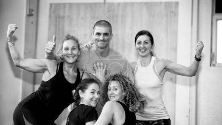 Photo for Four women doing trx training at the gym embracing the trainer. - Royalty Free Image