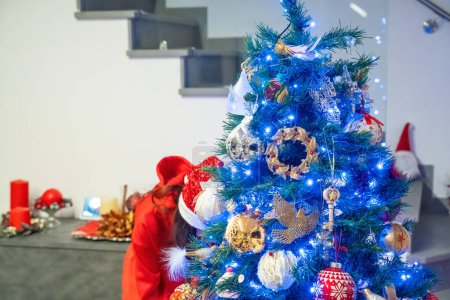 Téléchargez les photos : Décorer l'arbre de Noël dans une maison moderne avec des lumières colorées. - en image libre de droit