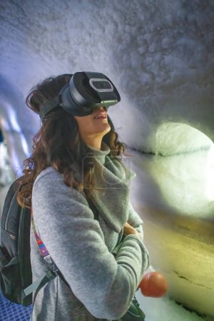 Foto de Mujer con visor de realidad virtual explorando paisaje helado. - Imagen libre de derechos