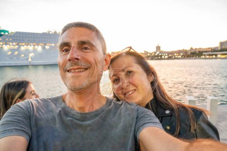Photo for A family taking pictures at sunset near a cruise ship. - Royalty Free Image