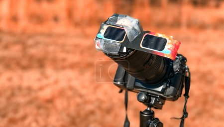 Eine speziell geschützte professionelle Kamera blickt während einer Sonnenfinsternis auf einem Landschaftspark in die Sonne.
