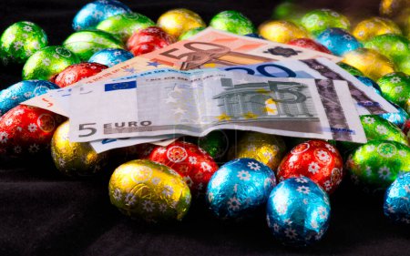 Foto de Huevos de Pascua pequeños con dinero en euros cubriéndolos. - Imagen libre de derechos