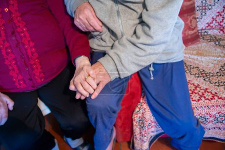 Téléchargez les photos : Deux personnes âgées main dans la main chez elles. - en image libre de droit