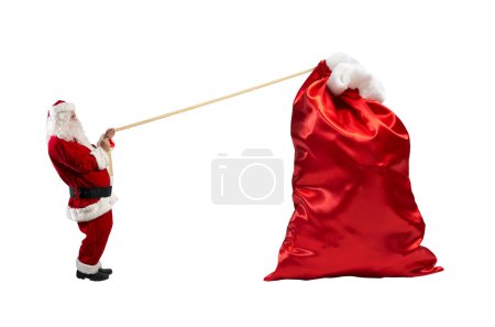Foto de Santa Claus tira de una cuerda para mover un saco grande - Imagen libre de derechos