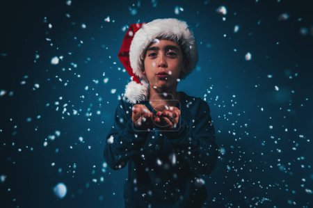 Photo for Child with xmas hat blows to make the snow fly - Royalty Free Image