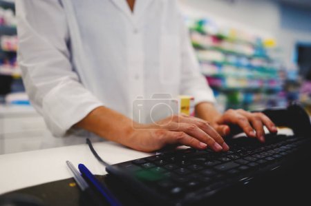 Téléchargez les photos : Une pharmacienne travaille au comptoir de pharmacie - en image libre de droit