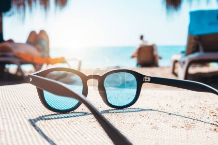 Téléchargez les photos : Sunglasses of a tourist on deckchair at a beach - en image libre de droit