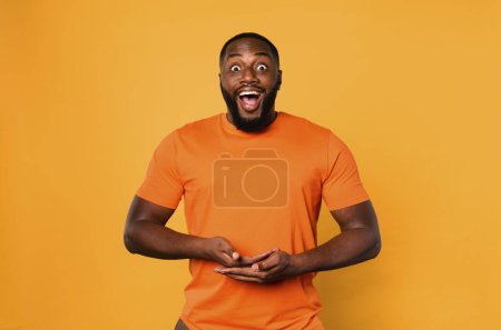 Photo for Happy afro man holds something. Orange background - Royalty Free Image