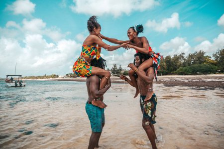 Foto de Amigos kenianos juegan en la playa con ropa típica local - Imagen libre de derechos