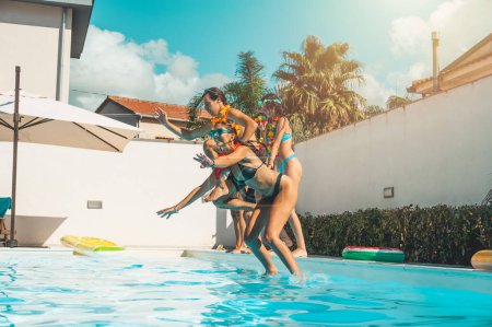 Téléchargez les photos : Groupe d'amis en maillot de bain profiter dans une piscine - en image libre de droit