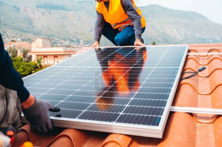 Foto de Trabajadores montan sistema con panel solar para electricidad y agua caliente - Imagen libre de derechos