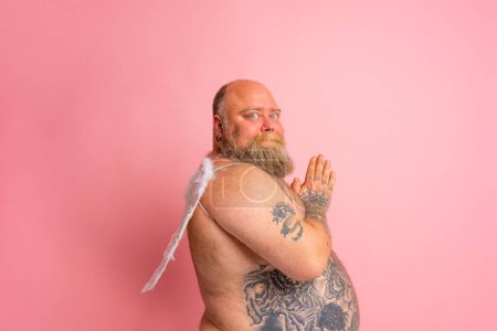 Téléchargez les photos : Man with beard ,tattoos and wings acts like an angel - en image libre de droit