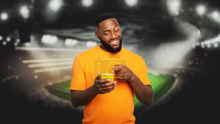 Foto de Hombre viendo un partido y apostando a través de su teléfono móvil - Imagen libre de derechos