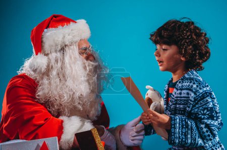 Téléchargez les photos : Père Noël écoute la demande de cadeaux d'un enfant pour Noël - en image libre de droit