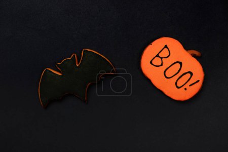 Photo for The hand-made eatable gingerbread Halloween  bat and pumpkin with boo inscription on black background - Royalty Free Image